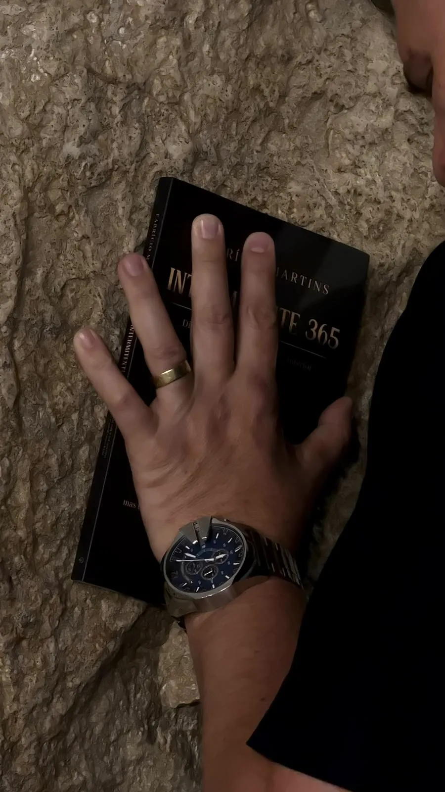 Mão sobre o livro Intermitente 365, encostado na pedra do Muro das Lamentações